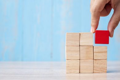 Businessman hand placing or pulling Red wooden block on the buil Businessman hand placing or pulling Red wooden block on the building. Business planning, Risk Management, Solution, strategy, different and Unique Concepts